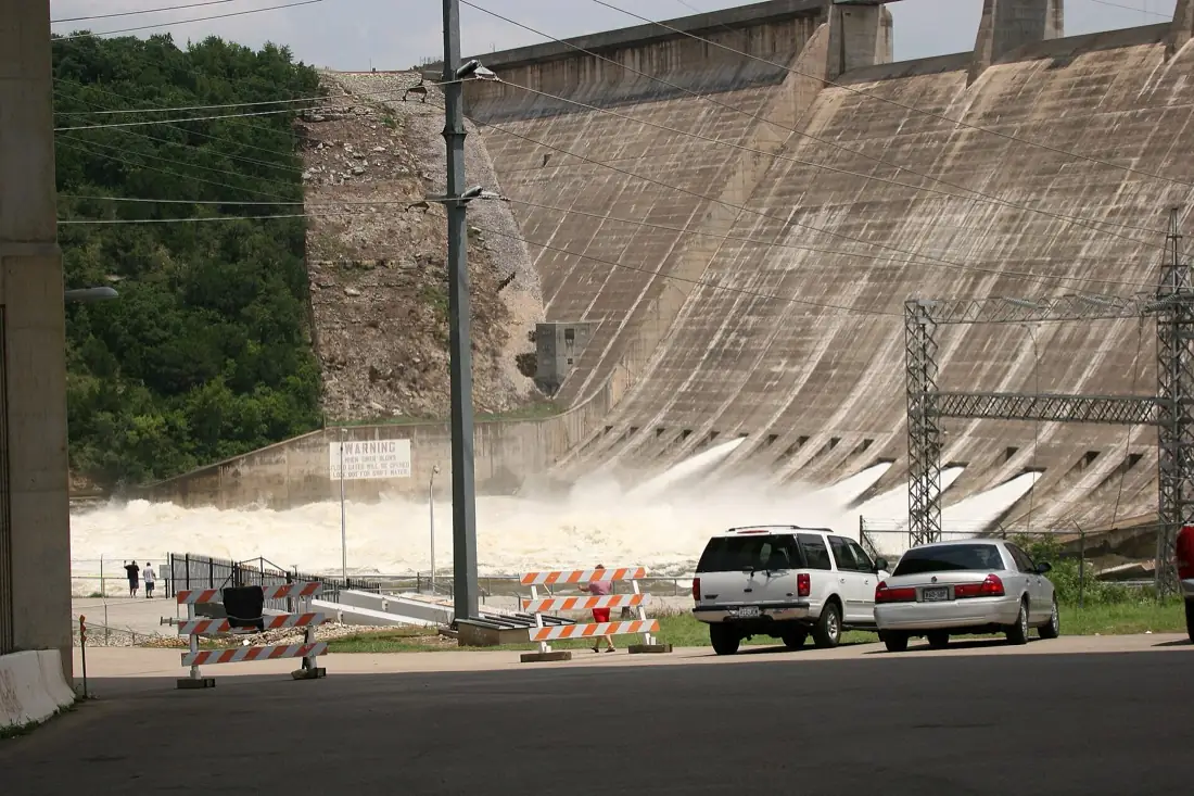Water discharging through open flood gates at the base of Mansfield Dam on Lake Travis, seen from the road below.